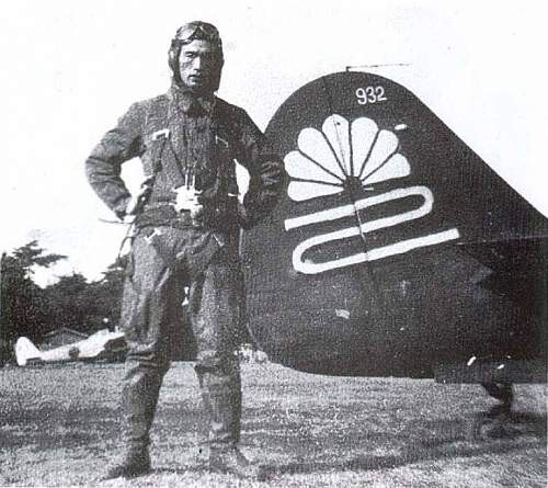 Un pilota in tenuta di volo davanti alla coda di un aereo, con l'emblema del crisantemo e il numero 932