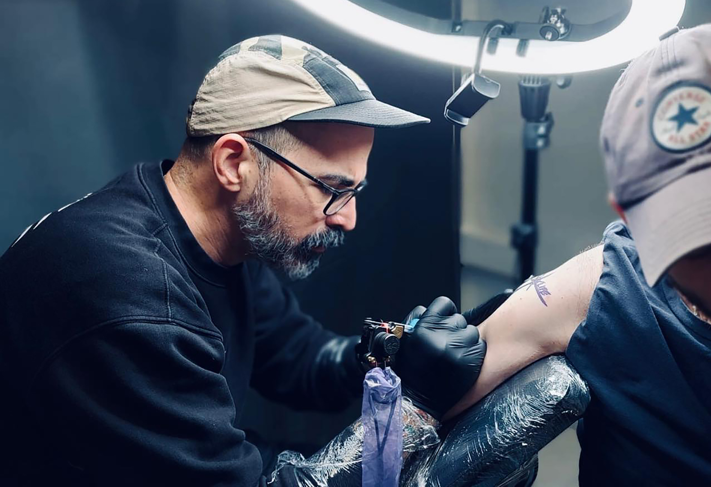 Maurizio What al lavoro durante una sessione di tatuaggio
